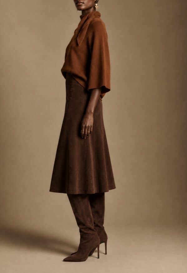 Model wearing Rust Cape Knit with brown skirt and high boots.