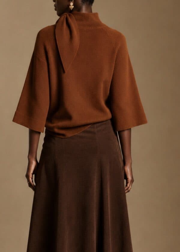 Rust coloured cape knit sweater with a tie detail at the neck.