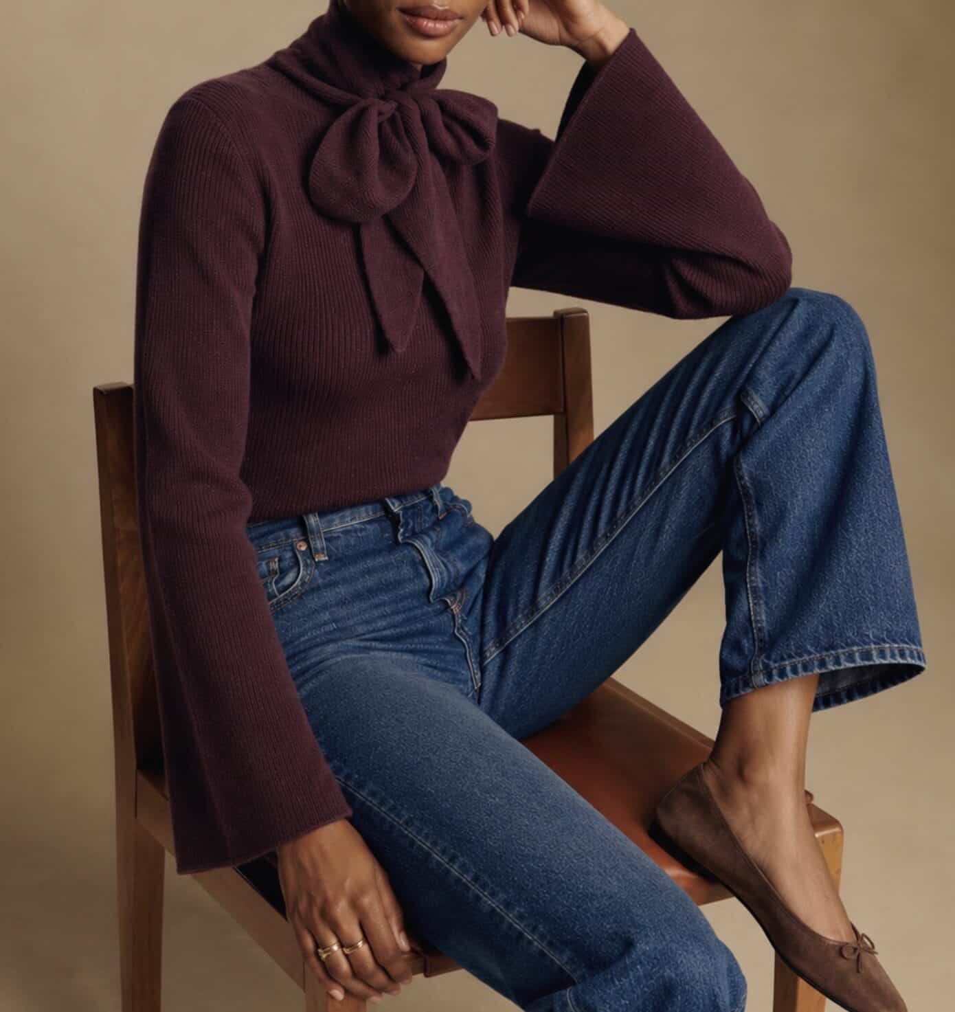 Elegant plum fitted knit with bow detail, paired with blue jeans and brown flats.