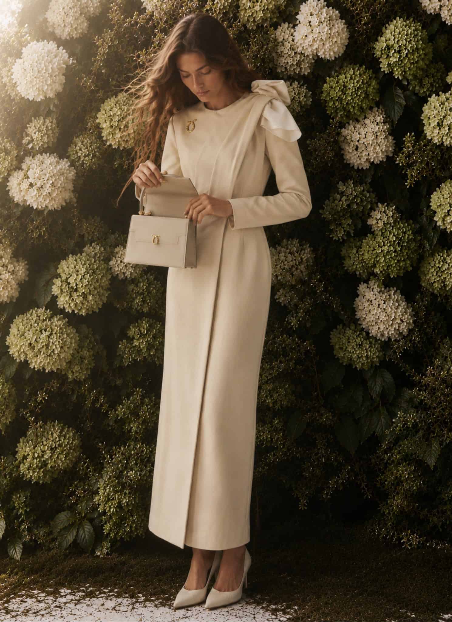 Draped Dress Coat 4 Woman in cream draped dress coat holding a clutch in front of floral backdrop.