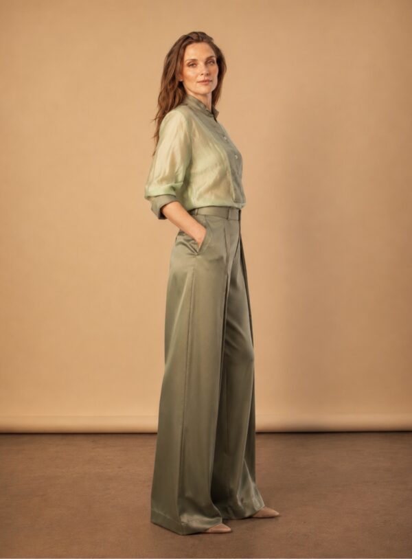 Elegant woman in sage green tux shirt and wide-leg trousers.