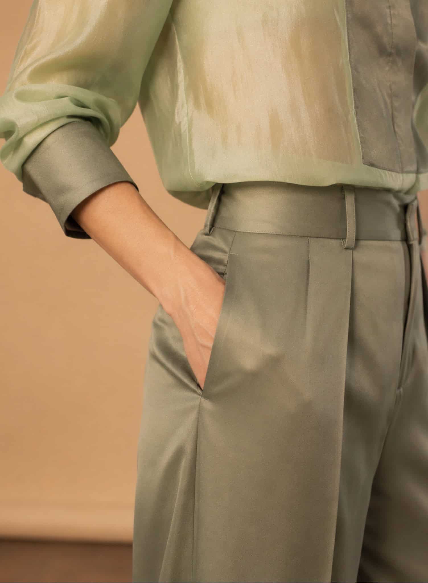 Sage Pleated Palazzo Pant 4 Close-up of a woman wearing a green satin tux shirt and matching trousers.
