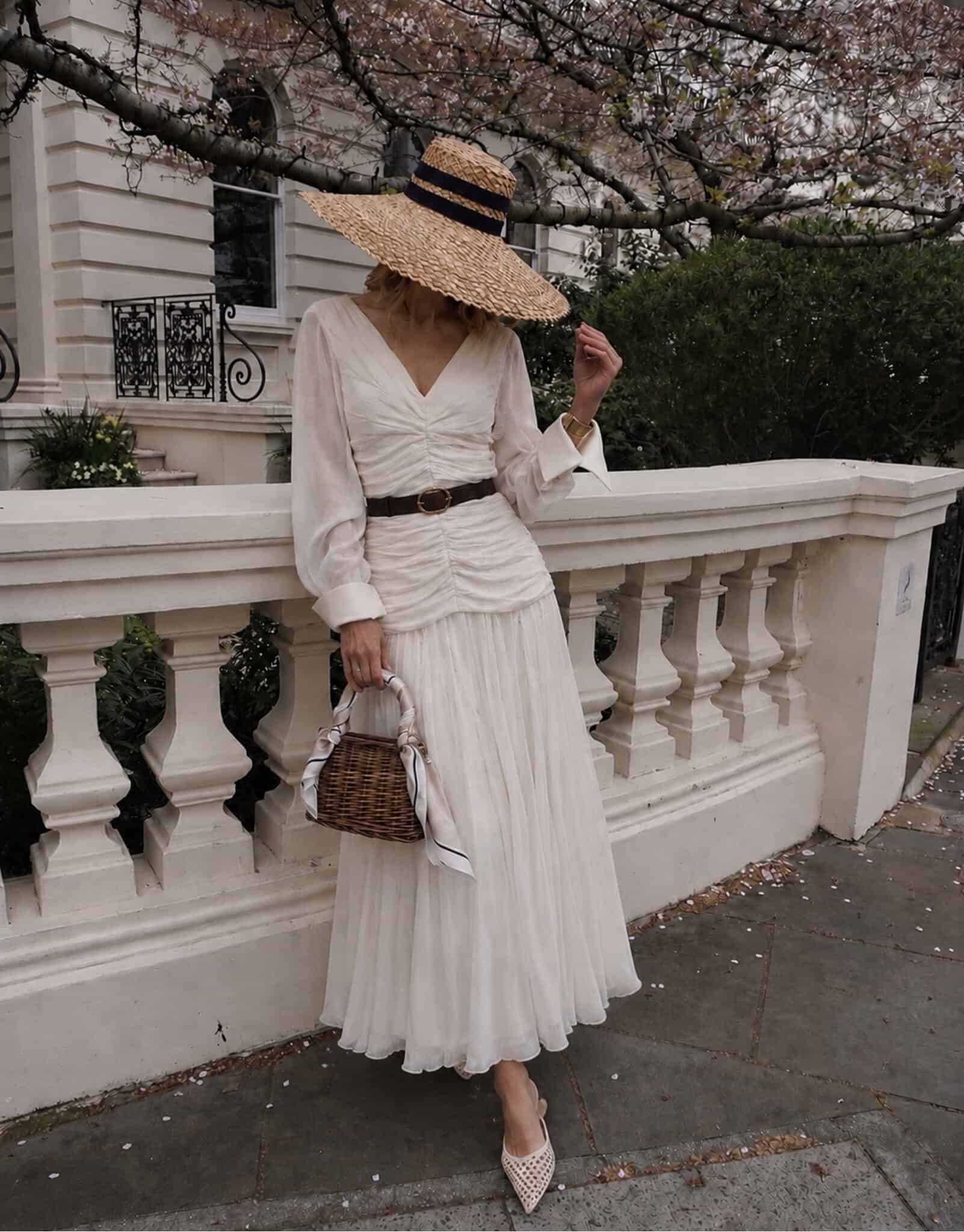 The Audrey 3 champagne tux shirt Woman in white dress with straw hat and wicker handbag on city street.