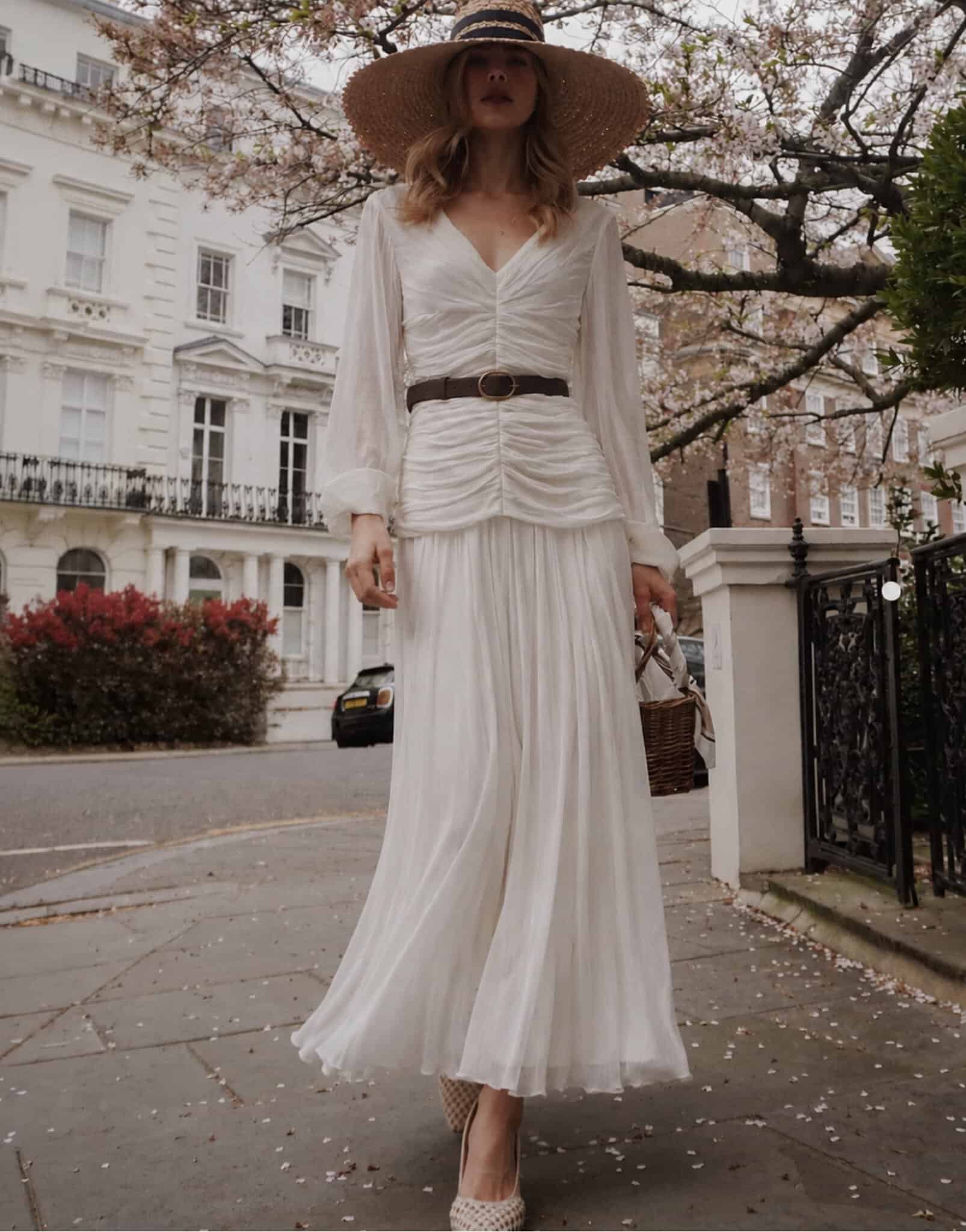 The Audrey 8 champagne tux shirt Woman in white maxi dress with wide-brim hat on city street in spring.