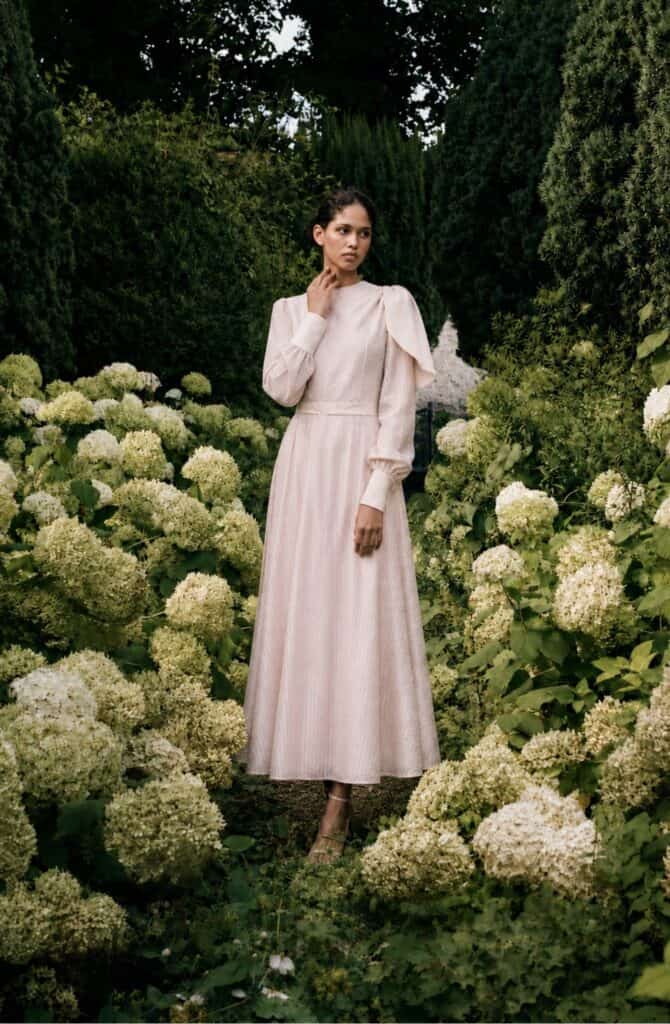 The Long-sleeved Catherine dress 11 Elegant long-sleeved dress by Aimee Joyce London in a garden setting.
