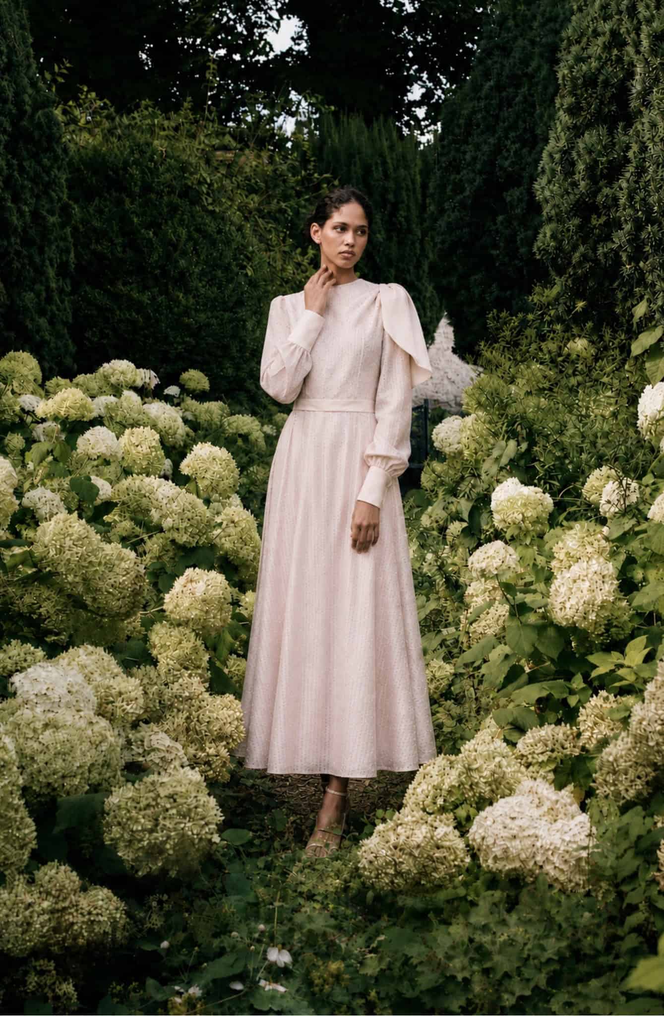 Elegant long-sleeved dress by Aimee Joyce London in a garden setting.