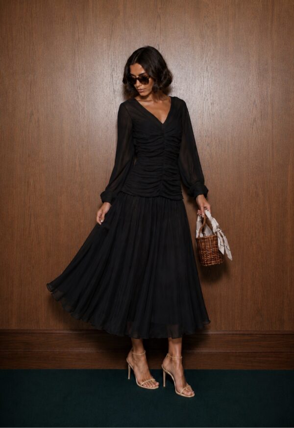 Black Audrey blouse with a ruched front, styled with a full midi skirt and a woven handbag.