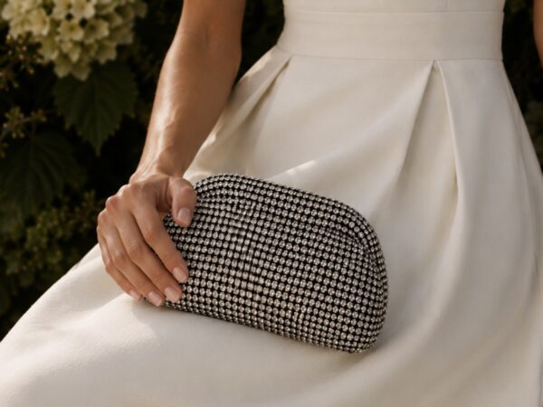 Elegant black and white patterned clutch bag held by a woman in a white dress.