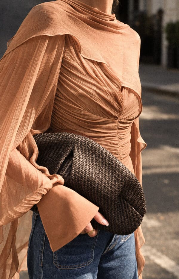 Detail of the tobacco Audrey blouse's ruched front, sheer sleeve and flared satin cuff.