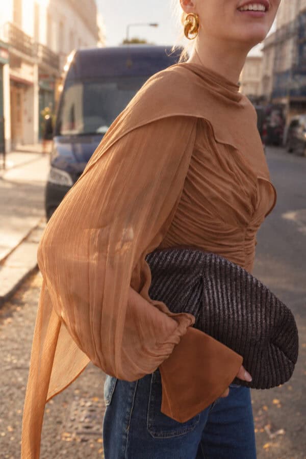 Side detail of the tobacco Audrey blouse's gathered sleeve, satin cuff and flowing chiffon cape.