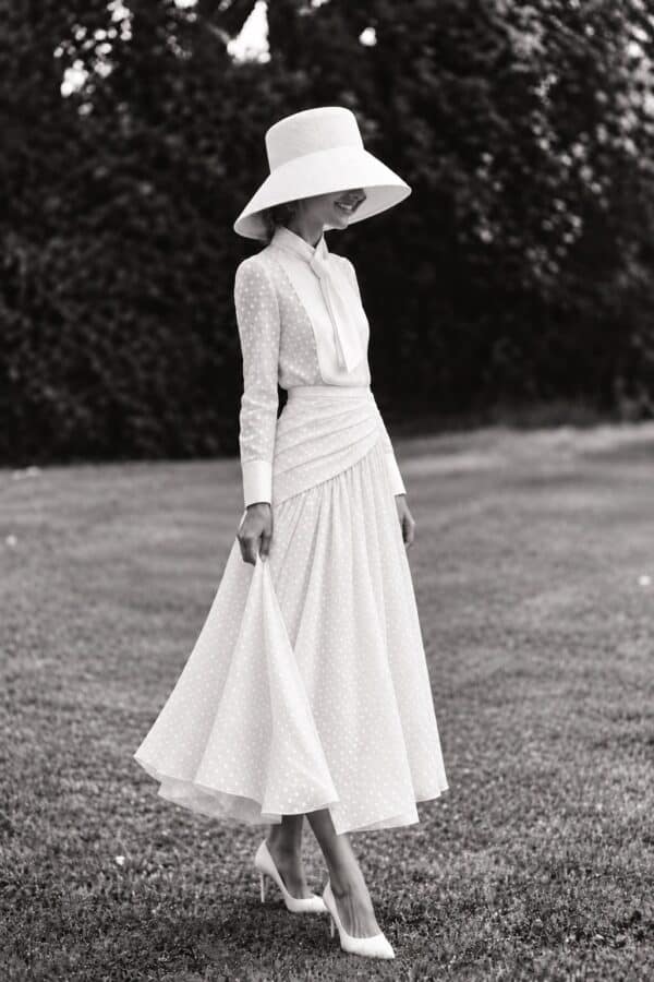 The white limited-edition Gilda set shown full length with a wide-brimmed hat in a garden.